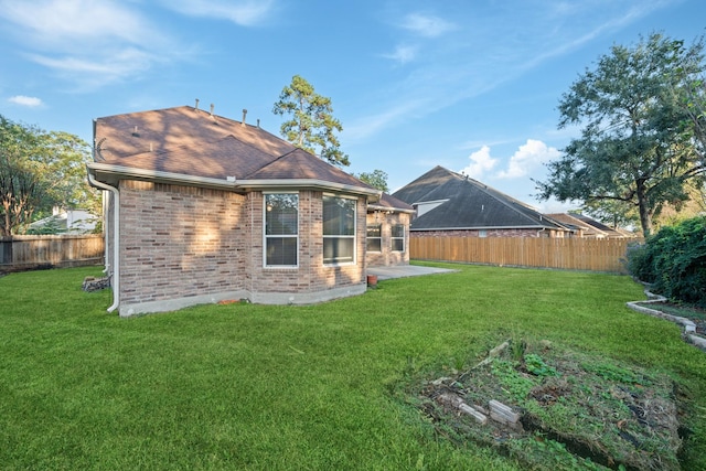 back of property featuring a patio, a fenced backyard, brick siding, a yard, and roof with shingles