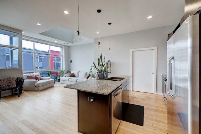 kitchen with a barn door, stainless steel appliances, light wood-type flooring, a sink, and recessed lighting