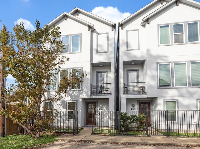 townhome / multi-family property with a fenced front yard and stucco siding