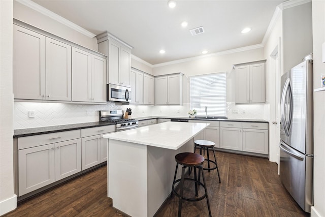 kitchen featuring appliances with stainless steel finishes, crown molding, a sink, and a breakfast bar area