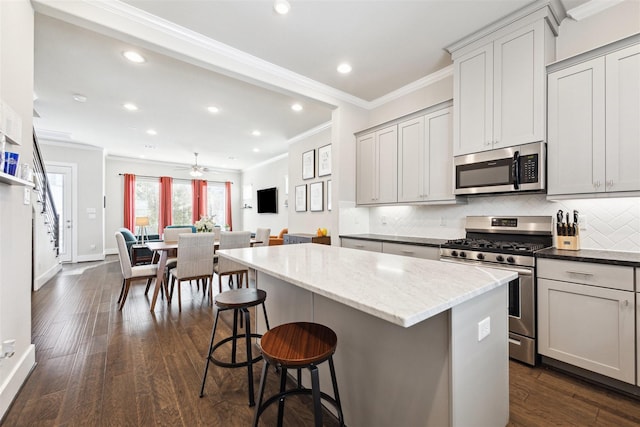 kitchen with dark wood-style floors, stainless steel appliances, backsplash, and crown molding