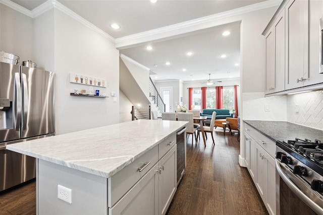 kitchen with decorative backsplash, dark wood-style floors, a kitchen island, appliances with stainless steel finishes, and light stone countertops