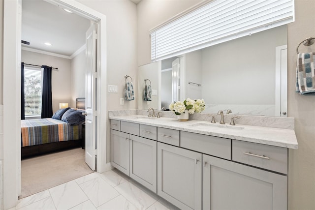 ensuite bathroom featuring marble finish floor, ornamental molding, ensuite bath, and a sink