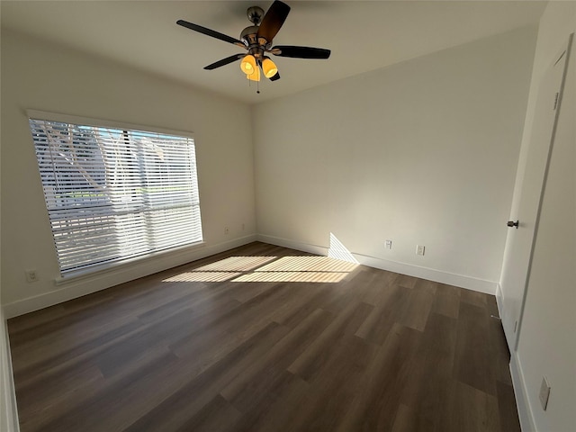 empty room with dark wood-style flooring, a ceiling fan, and baseboards