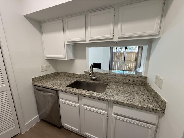 kitchen featuring light stone counters, dark wood-style flooring, stainless steel dishwasher, white cabinetry, and a sink