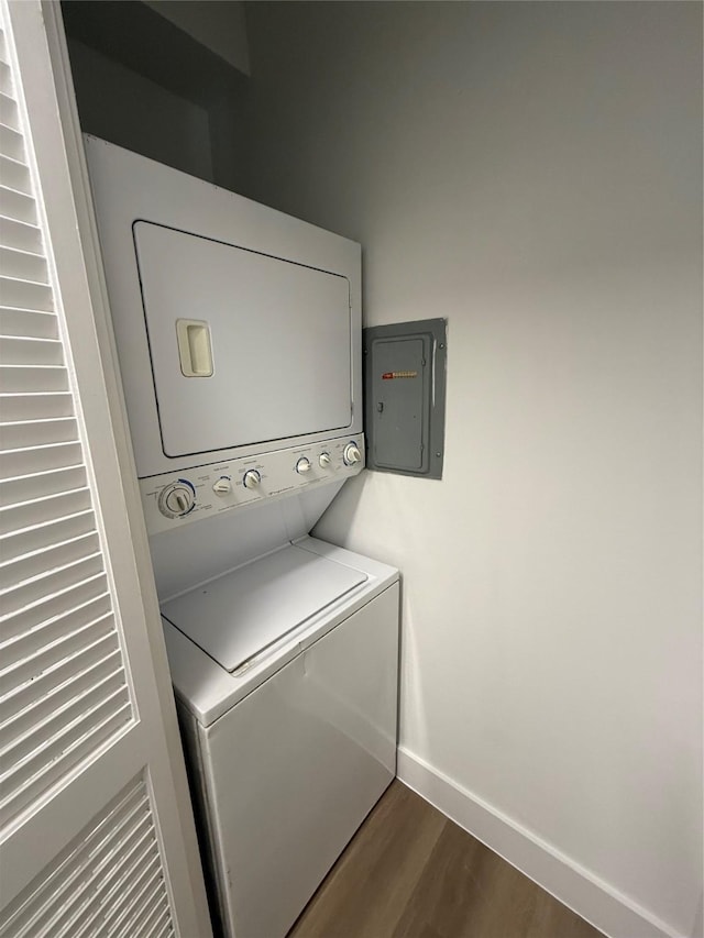 laundry room with stacked washer and clothes dryer, baseboards, and dark wood-style flooring