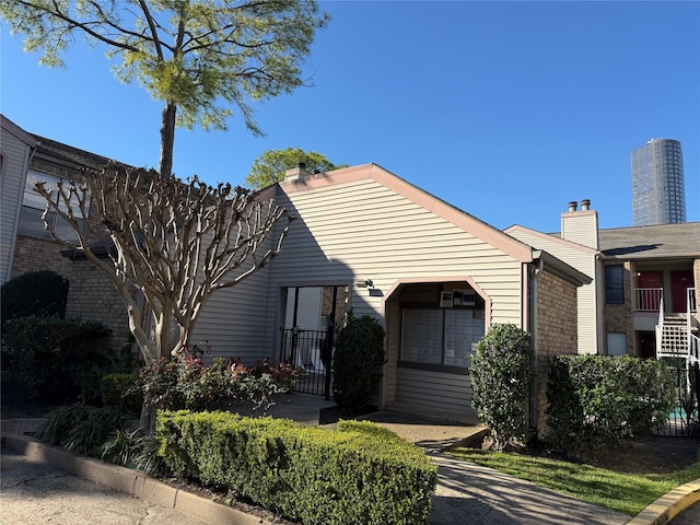 view of front facade featuring a chimney and brick siding