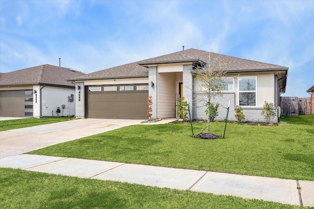 prairie-style home with a shingled roof, an attached garage, fence, driveway, and a front lawn