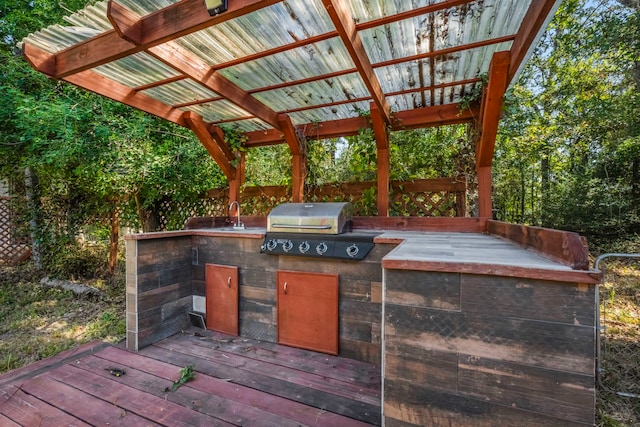 view of patio / terrace featuring area for grilling, a wooden deck, an outdoor kitchen, and a pergola