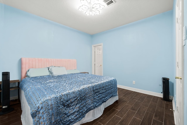 bedroom with wood finish floors, visible vents, and baseboards