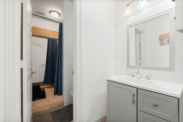 bathroom featuring toilet, visible vents, a shower with shower curtain, and vanity