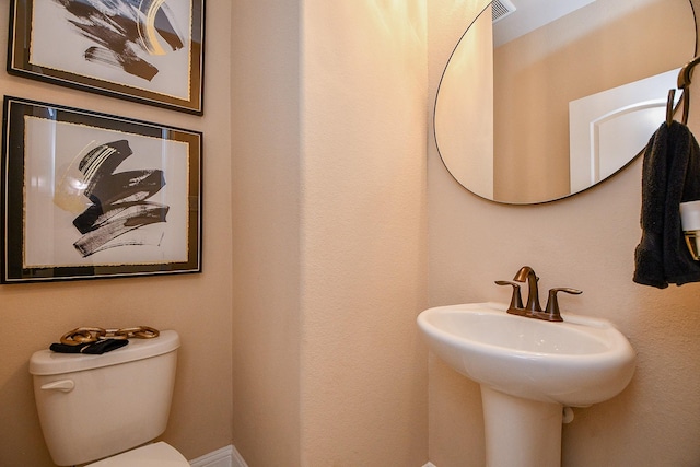 half bathroom featuring toilet and a sink