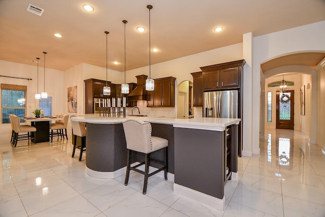 kitchen with arched walkways, marble finish floor, and stainless steel refrigerator with ice dispenser