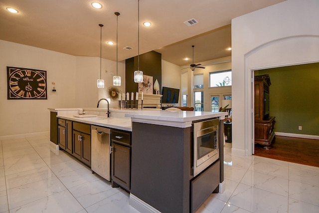 kitchen with marble finish floor, a center island with sink, a sink, appliances with stainless steel finishes, and light countertops