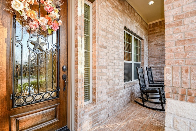 property entrance featuring a porch and brick siding