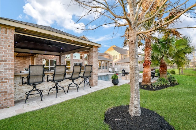 view of yard with outdoor dry bar, a patio area, a fenced backyard, and ceiling fan