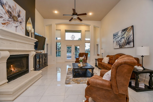 living area featuring arched walkways, marble finish floor, a fireplace, and ceiling fan