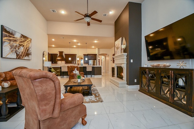 living room with visible vents, arched walkways, marble finish floor, and a ceiling fan