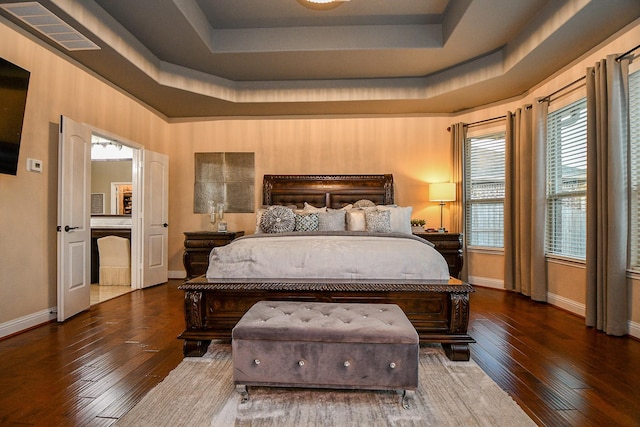 bedroom with visible vents, a raised ceiling, baseboards, and wood-type flooring