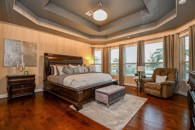 bedroom featuring a raised ceiling, multiple windows, visible vents, and wood-type flooring