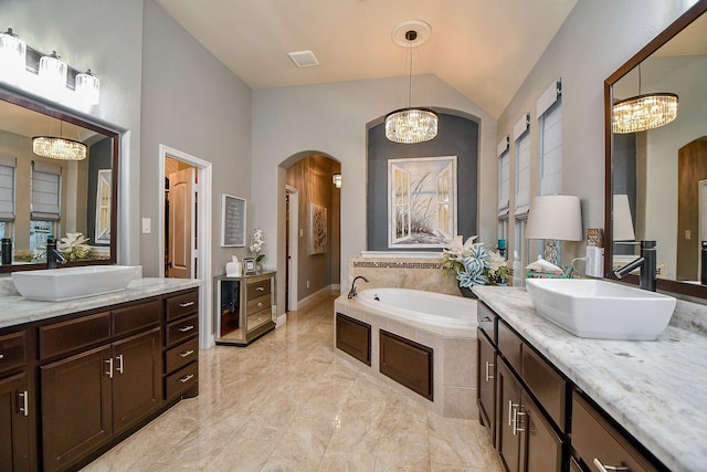 full bath with a sink, lofted ceiling, a notable chandelier, and a bath