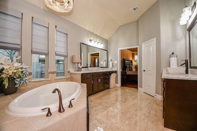 ensuite bathroom with visible vents, a garden tub, two vanities, high vaulted ceiling, and a sink