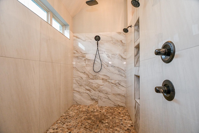 bathroom with a tile shower and lofted ceiling