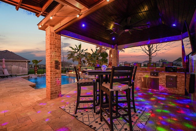 view of patio with fence, a gazebo, exterior kitchen, a fenced in pool, and ceiling fan