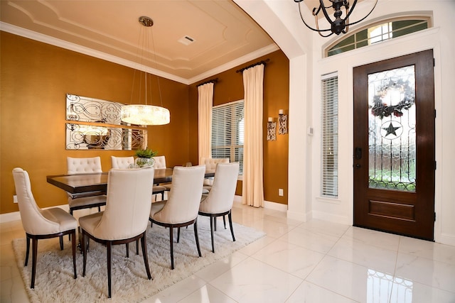 dining space featuring crown molding, baseboards, arched walkways, and a chandelier