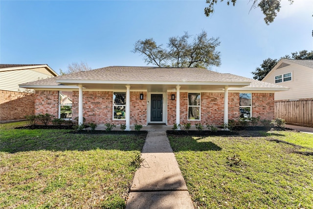 ranch-style house with a shingled roof, fence, a front lawn, and brick siding