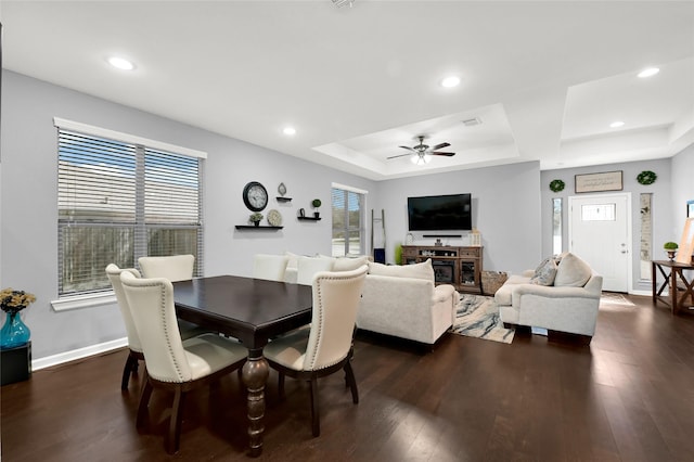 dining space with ceiling fan, recessed lighting, dark wood-style flooring, baseboards, and a tray ceiling