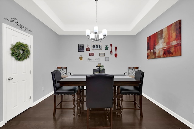 dining room featuring a chandelier, a tray ceiling, wood finished floors, and baseboards