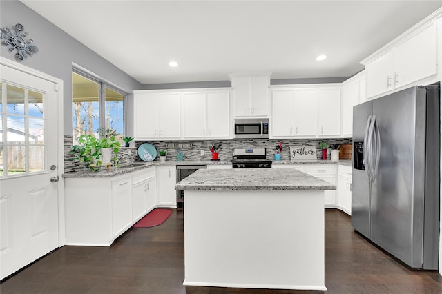 kitchen featuring appliances with stainless steel finishes, backsplash, light stone countertops, and a center island