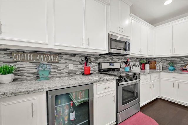 kitchen with backsplash, appliances with stainless steel finishes, white cabinetry, light stone countertops, and beverage cooler