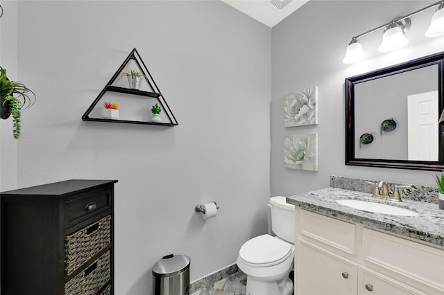 bathroom featuring baseboards, vanity, and toilet