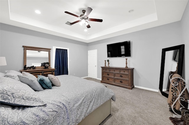 bedroom featuring a tray ceiling, carpet flooring, and baseboards