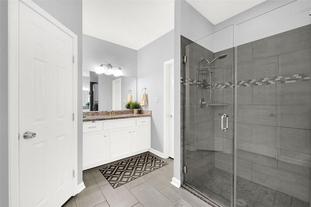 bathroom featuring baseboards, a shower stall, vanity, and tile patterned floors