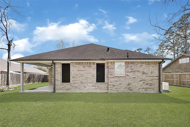 rear view of house featuring brick siding, a lawn, a fenced backyard, and a patio