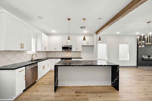 kitchen with dark countertops, visible vents, appliances with stainless steel finishes, and a sink