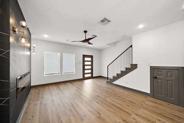 foyer with light wood-type flooring, stairway, baseboards, and visible vents