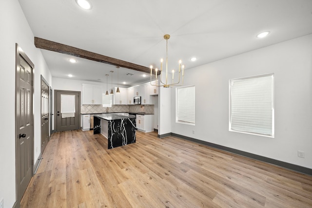 kitchen featuring dark countertops, stainless steel microwave, backsplash, white cabinetry, and beamed ceiling