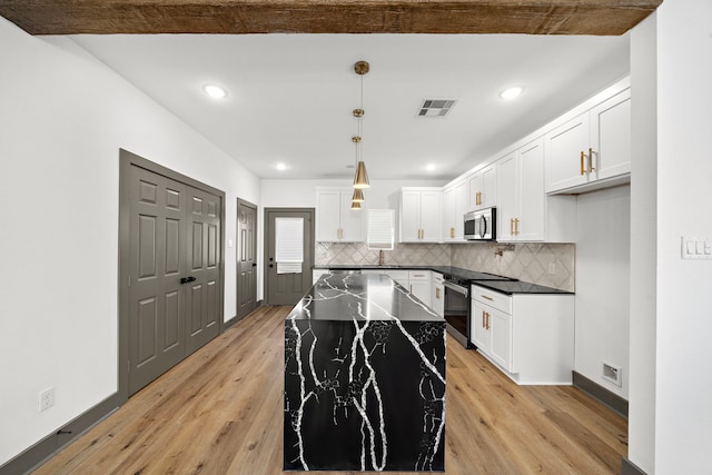 kitchen featuring a sink, visible vents, appliances with stainless steel finishes, light wood-type flooring, and dark countertops