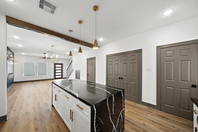 kitchen featuring light wood finished floors, visible vents, open floor plan, beamed ceiling, and white cabinetry