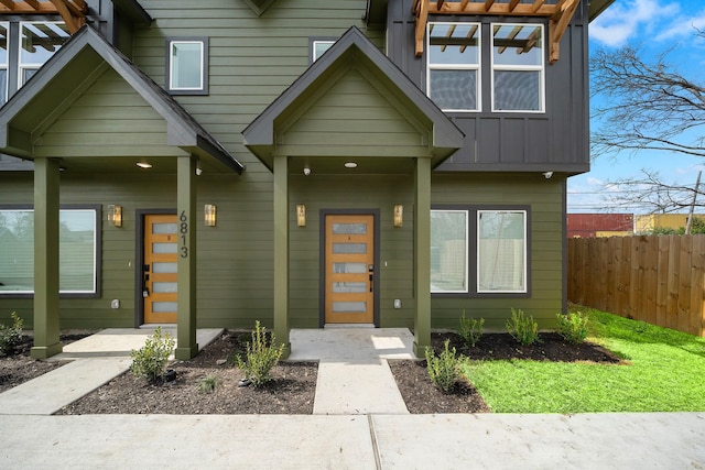 doorway to property with board and batten siding and fence