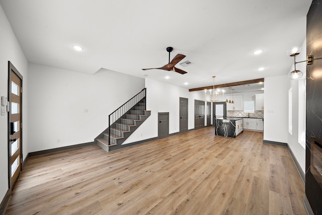 unfurnished living room featuring light wood finished floors, stairs, baseboards, and recessed lighting