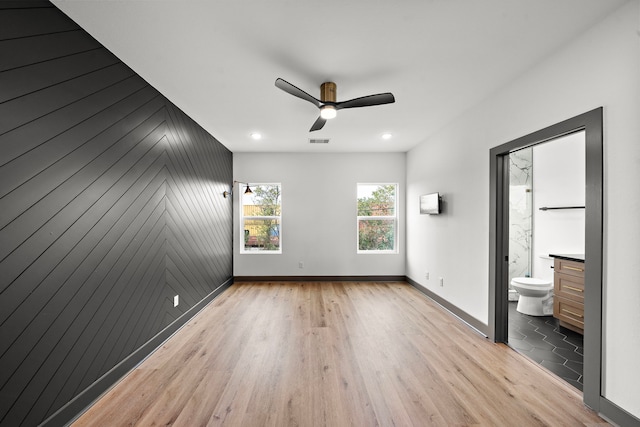 unfurnished bedroom with visible vents, baseboards, a ceiling fan, ensuite bathroom, and light wood-style floors