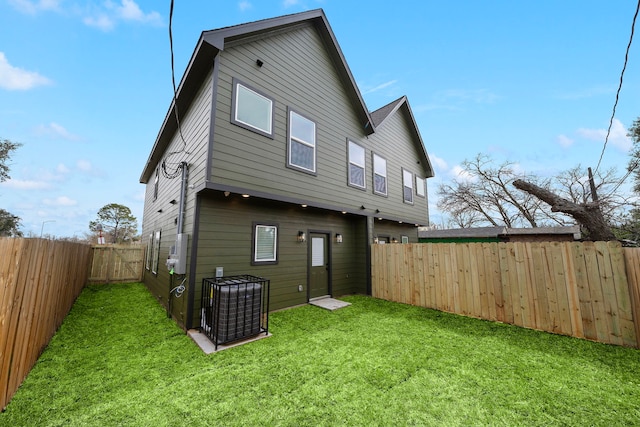 rear view of property featuring a lawn and a fenced backyard