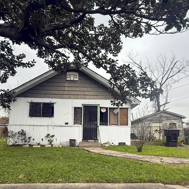 bungalow-style home with entry steps and a front lawn