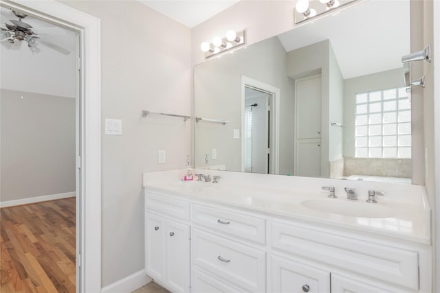 full bath with a ceiling fan, wood finished floors, a sink, and double vanity