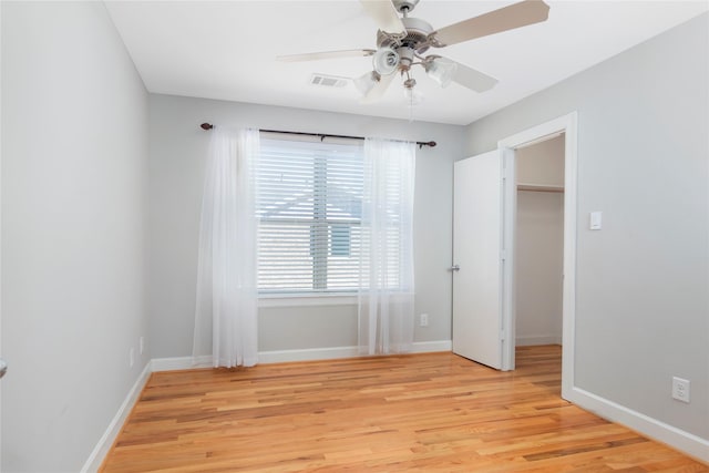 unfurnished bedroom featuring light wood-type flooring, baseboards, visible vents, and a walk in closet